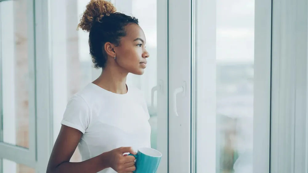 A woman pausing with a warm drink and allowing herself a quiet moment of rest